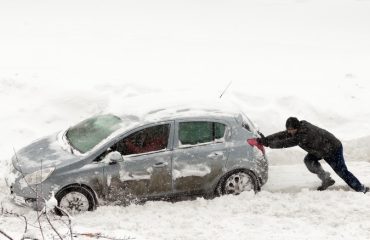 Person pushing car in snow