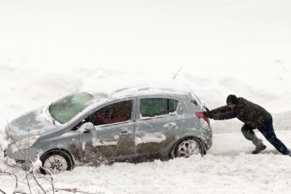 Person pushing car in snow