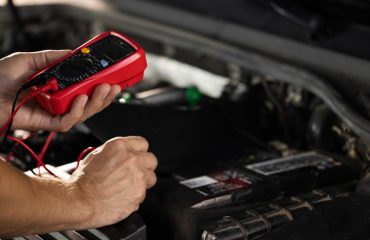 mechanic checking battery with multimeter