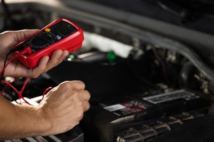 mechanic checking battery with multimeter