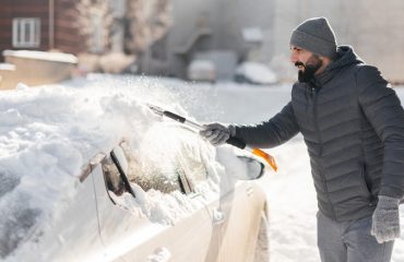 man scraping off snow from car