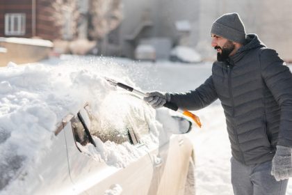 man scraping off snow from car