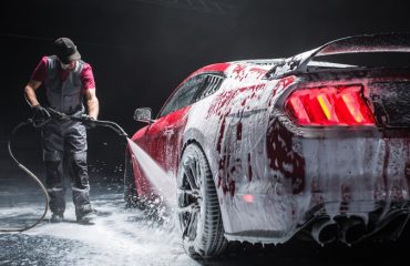 Man rinsing foam-covered car