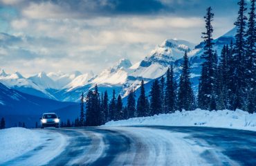 Car driving down snowy road