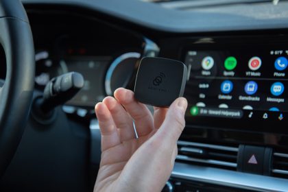 AAWireless Android Auto adapter held in front of dashboard and android auto screen